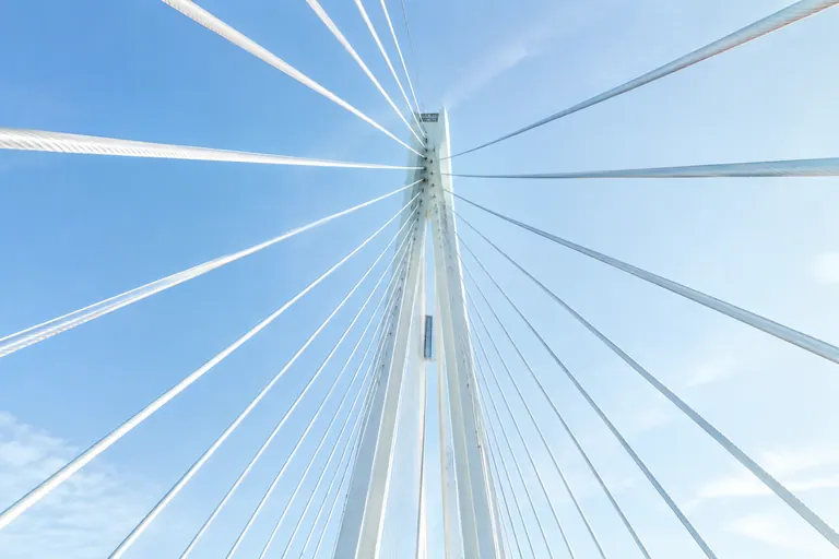 Haubans blancs d'un pont convergeant vers un pylône, symbole de liens qui portent